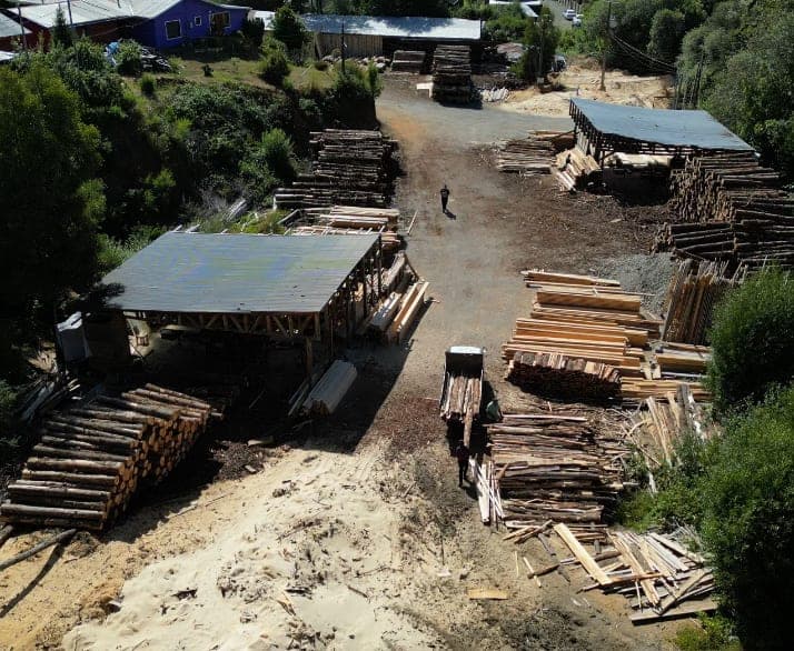 Vista aérea de las instalaciones de Aserradero El Arenal en el sector El Arenal, con galpones y pilas de madera aserrada
